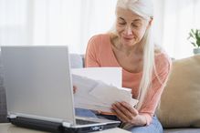 Senior woman going over bills with a laptop