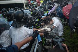 Hong Kong police, representing the political power of the state, spray and beat a member of the Occupy Central with Peace and Love movement, representing Marx's theory of class conflict.