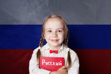 Learn russian language. Child girl student with book against the russian flag background
