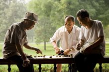 Three men playing board game outdoors smiling