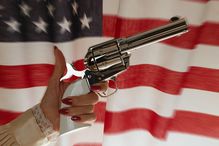 Woman holding antique cavalry pistol, close-up, USA flag in background