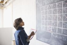 A woman figuring out a monthly schedule on a chalkboard