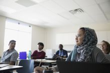 Focused ESL student in hijab listening to lesson in classroom