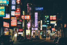 A Chinese city at night with many lit up signs.