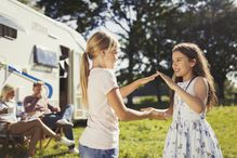 Sisters playing pat-a-cake outside sunny motor home