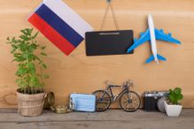 Travel time concept - blank blackboard, flag of the Russia, camera, airplane model, little bicycle and suitcase, compass on wooden background