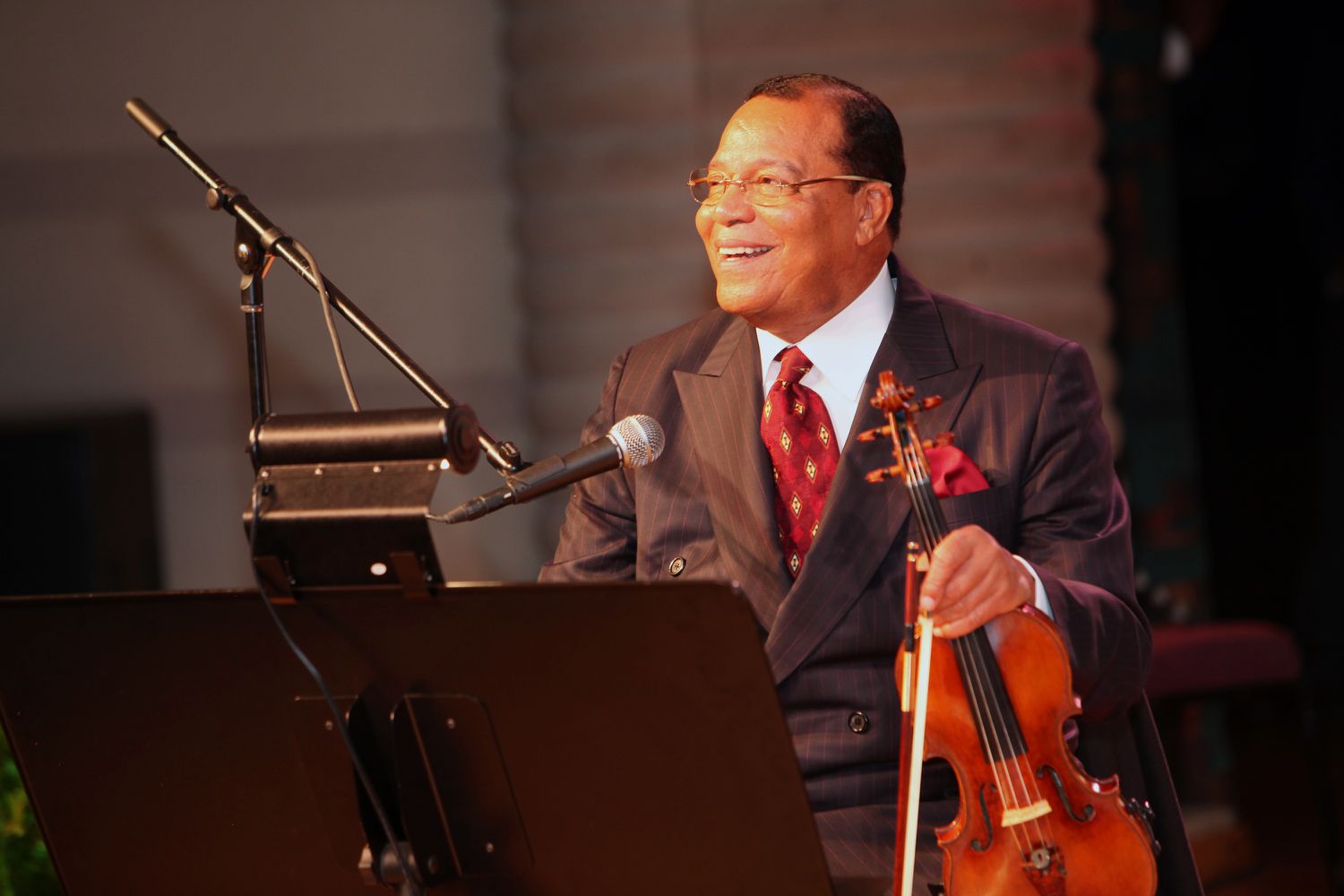 Minister Louis Farrakhan holding a violin and smiling