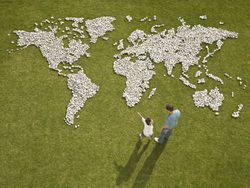 Father and son looking at a world map made with rocks on the grass.