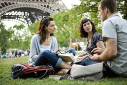 Group of people talking as they sit under the Eiffel Tower.