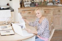 Smiling woman at table with old photographs and genealogical tree