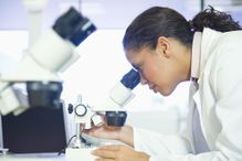 Woman looking through a microscope in a lab.