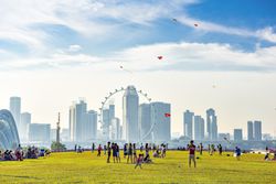 People play in a park with the skyline of Singapore in the background