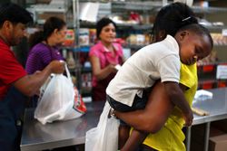 Young mother holding baby while buying groceries