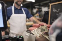 Customer at register paying with cash.