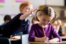 Boy about to pull hair of girl sitting in front of him