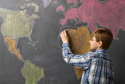 Child drawing world map on a blackboard
