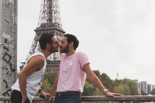 Two men kissing with the Eiffel Tower in the background.