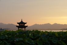 Chinese pagoda at sunset with mountains in the distance.