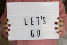 Woman holding light box with "Let's Go" message