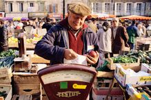 A vendor at a French market weighs some produce