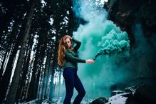 A young woman in a forest holding a distress flare