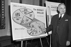 President Truman pointing at a budget pie chart, black and white photograph.