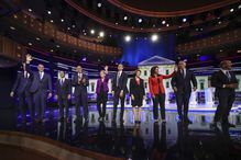 Several candidates waving onstage at a debate