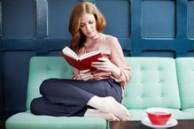 Woman reading a book on sofa.