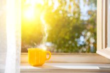 Cup on the window with sun and defocused nature background