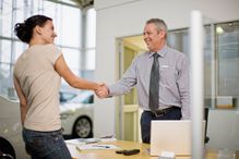 Woman shaking hands with car salesman