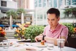 Man looking at watch while eating outside