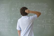 Teenaged boy looking at math equations on a blackboard