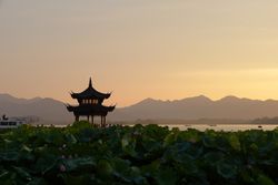 Chinese pagoda at sunset with mountains in the distance.