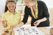 Grandmother and granddaughter painting Japanese symbols