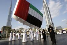 Emirati men and women carry UAE flag in front of Burj Khalifa during UAE National Day, Dubai