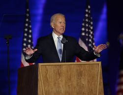 Joe Biden standing at a podium with two flags behind him