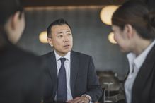 Japanese businessman talking to colleagues in business meeting, candid portrait