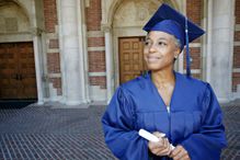 A smiling woman holding a diploma in a graduation gown