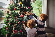 Small children decorate a Christmas tree