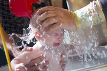 Priest pours water on the infant at baptism