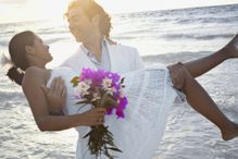 Bridal couple near Tulum, Mexico on the beach with the sun and water in the background.