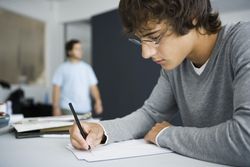 Student writing at desk