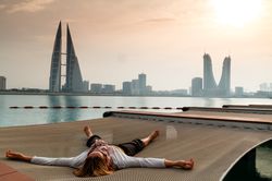 A person is sprawled out on a net at Pier Against Sky overlooking a Bahrain cityscape