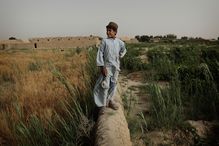 A Pashtun boy stands on a mud wall in his family&#39;s farm fields June 3, 2010 in Walakhan, a village south of Kandahar, Afghanistan