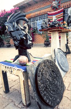 Handmade obsidian aztec head statue on sale amongst other mesoamerican artifacts.