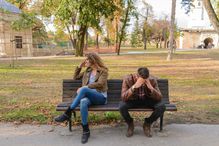 Woman and man on a bench in the park having an argument.