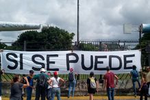 People gathered around 'sí se puede' sign.