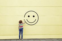 Girl drawing smiley face on to a wall