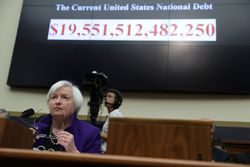 Federal Reserve Chairwoman Janet Yellen sitting in front of the national debt clock