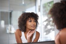 Attractive young woman looking at herself in the mirror